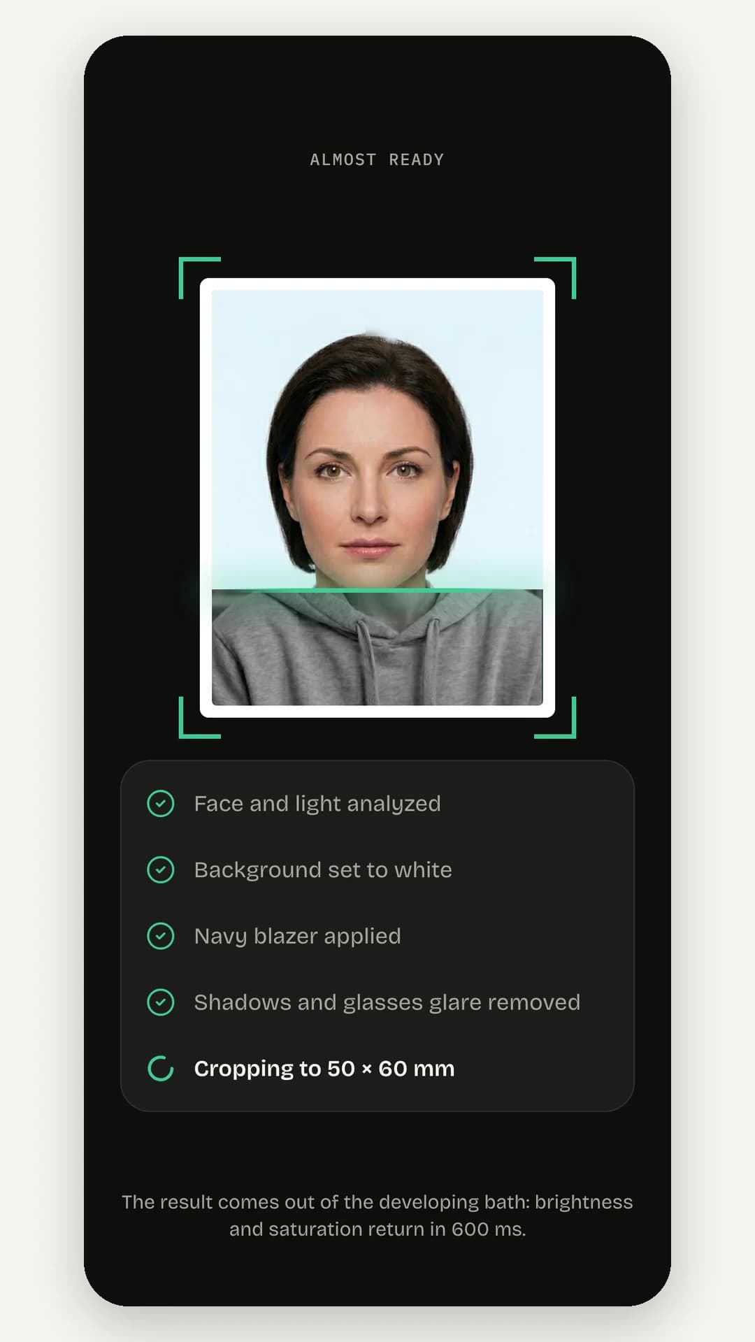 The generating screen: the photo in viewfinder brackets with a scanning line and a checklist reading face and light analyzed, background set to white, blazer applied, glare removed and cropping to 50 × 60 mm